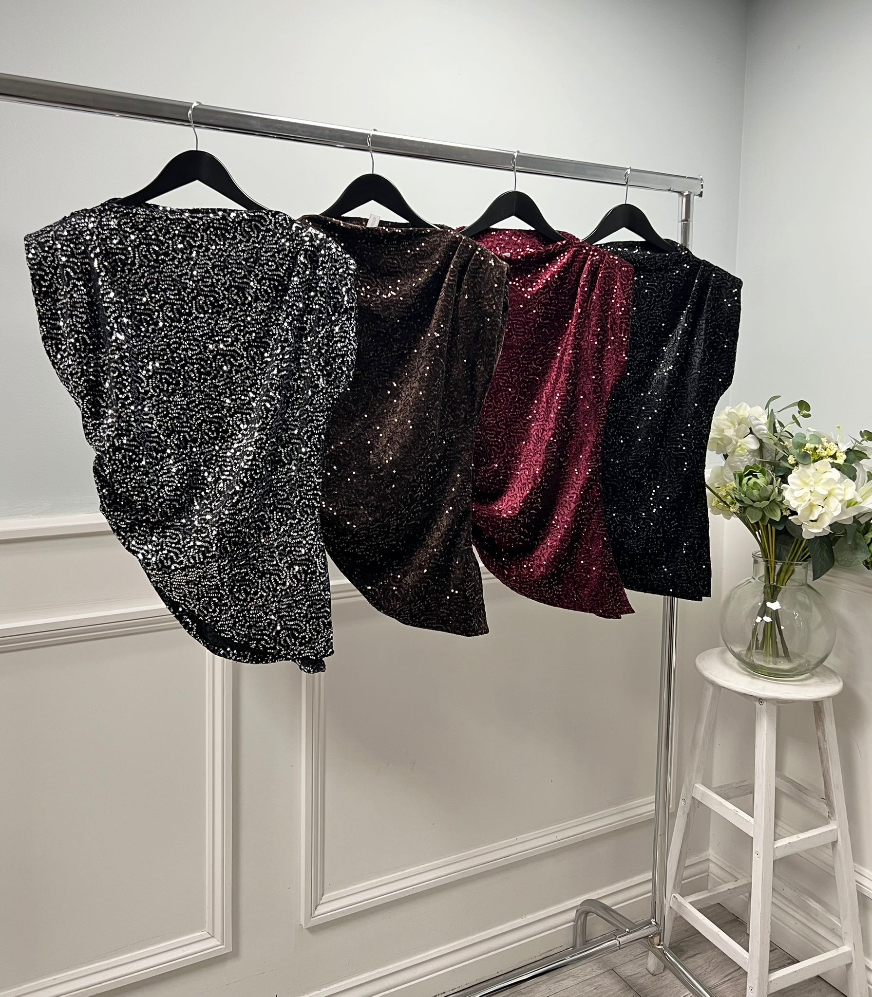 Sleeveless sequin top with padded shoulders and an asymmetric drape hem