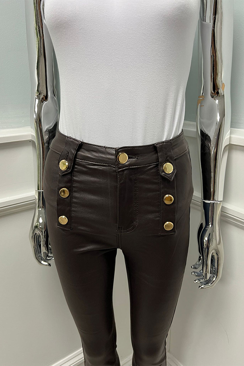 Modern polish — high-waist brown leather pants with bold gold buttons
