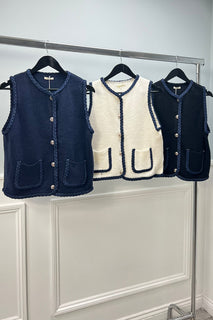 sleeveless cardigan with navy braided trim and front patch pockets.