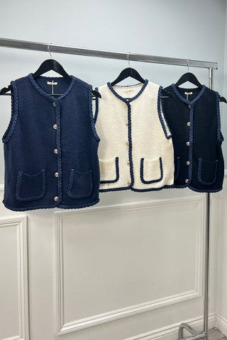 sleeveless cardigan with navy braided trim and front patch pockets.